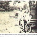 Betty Sue Keith and Joyce Faye Taylor sitting on Charlie Bailiffs buzz saw